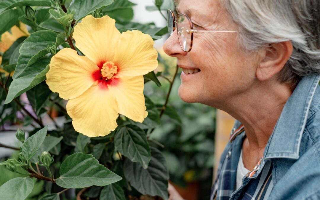 Senior Woman Wearing Glasses Smells Flower_The Grove on Forest Lane