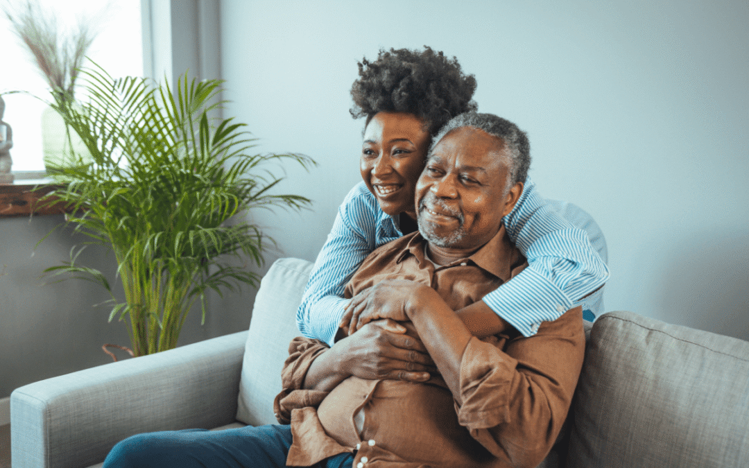 Loving father and daughter together on sofa. Beautiful woman with her father as they both smile. Beautiful young woman embracing her father. Senior African American man and daughter